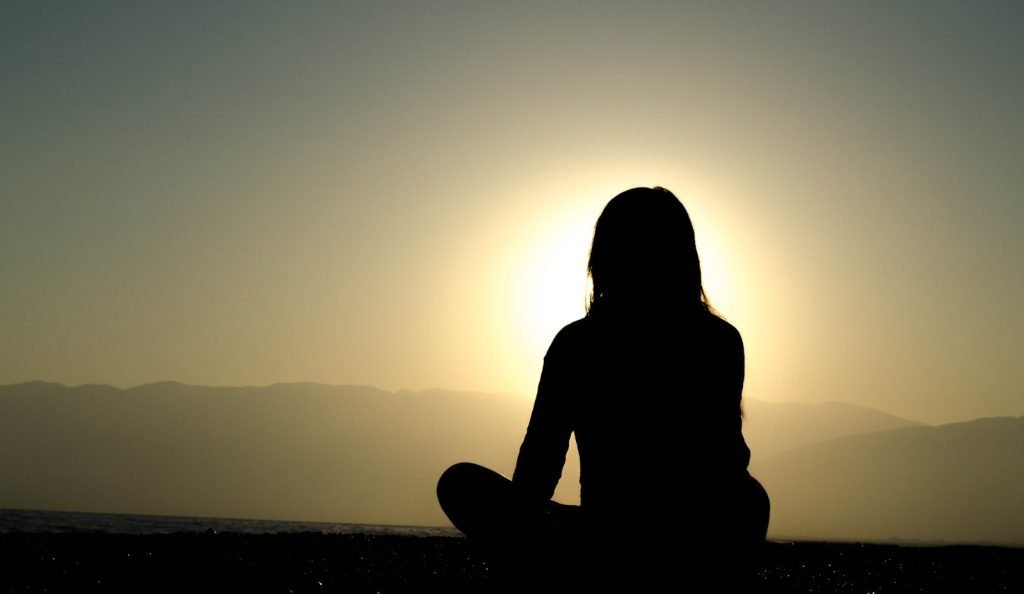 woman sitting and meditating on sand